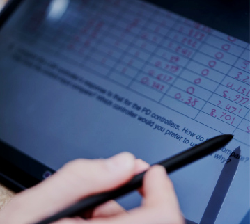 close up of hand with pen pointing at a screen displaying scores