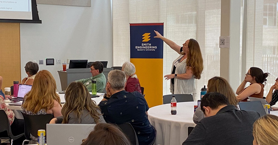 Keynote speaker Sharona Krinsky presenting to an audience in a conference room beside a Smith Engineering banner.