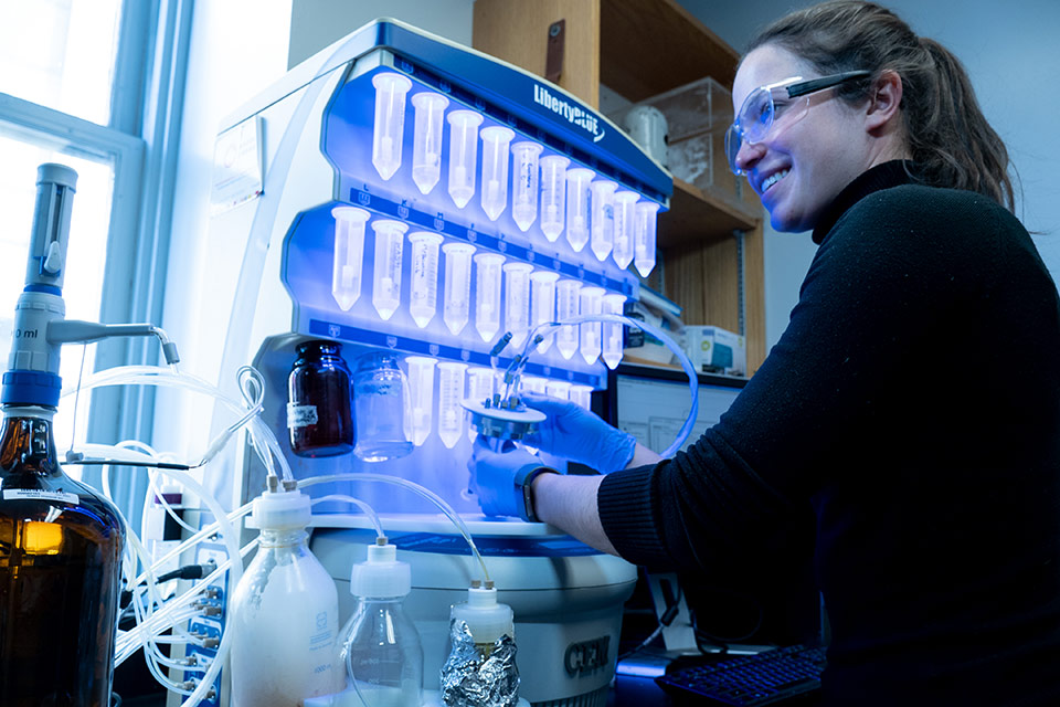smiling woman in lab with glowing samples