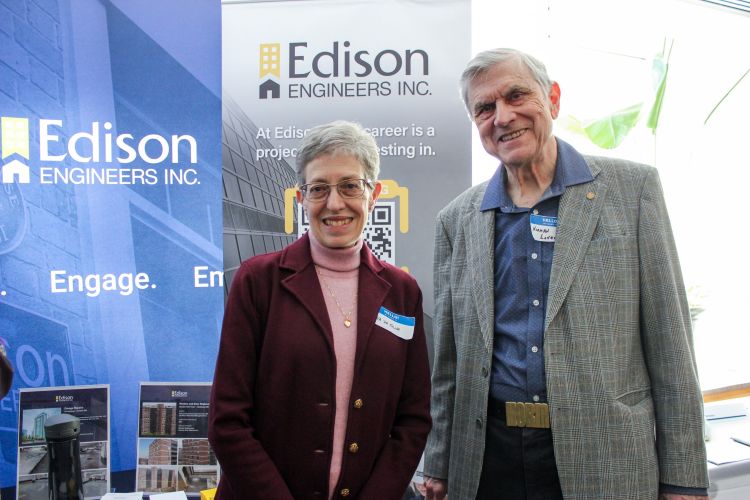 Man and woman standing in front of banners at a trade show