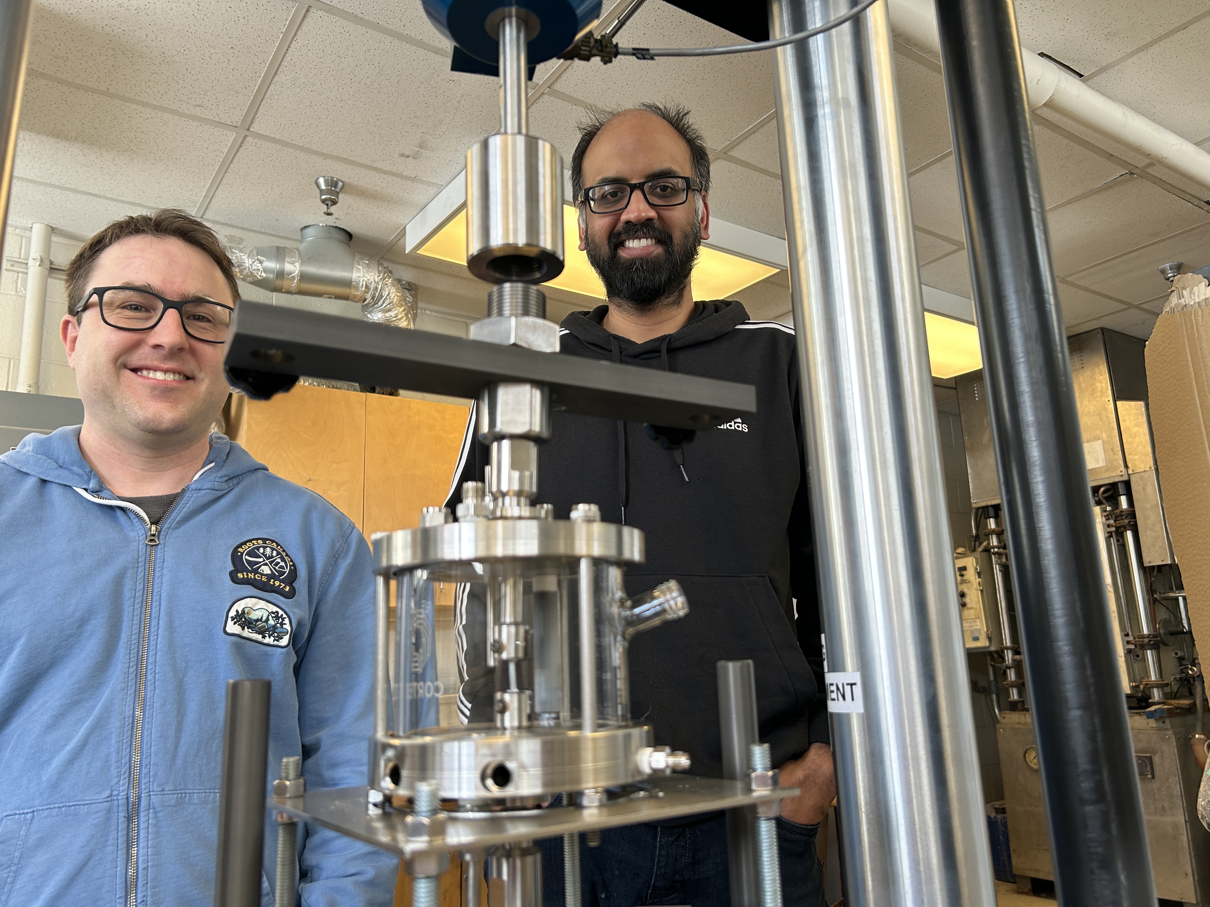 two men are standing in a lab with a piece of equipment.